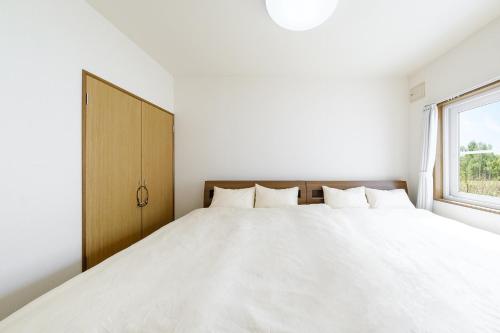 een slaapkamer met een groot wit bed en een raam bij Landmark Annex in Furano