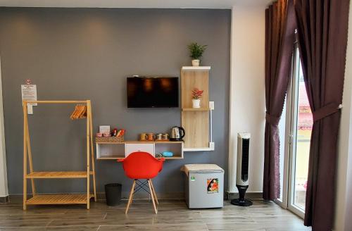 大叻的住宿－Ngô Gia Home，一间设有红色椅子和墙上电视的房间
