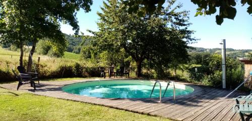 une petite piscine avec une terrasse en bois à côté d'une cour dans l'établissement Gite LaMothe en Aveyron, à Salles-Courbatiès