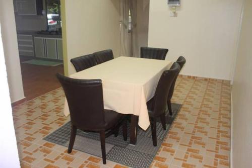 einen Esstisch mit Stühlen und einem weißen Tischtuch in der Unterkunft Wafi Guesthouse in Kuala Terengganu