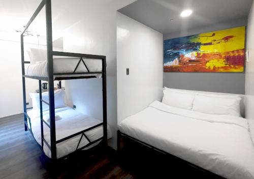 1 dormitorio con 2 literas y una pintura en mySTAY Hotel BGC South en Manila