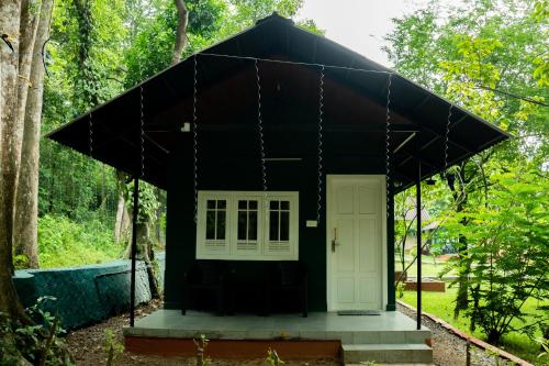 a black house with a white door in a forest at The Nest Thattekad in Thattakād