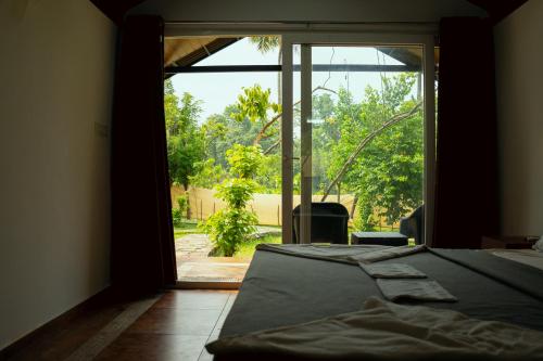 Habitación con cama y puerta de cristal grande. en The Nest Thattekad, en Thattakād