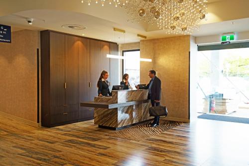 two people standing at a reception desk in a lobby at The Sebel Wellington Lower Hutt in Lower Hutt