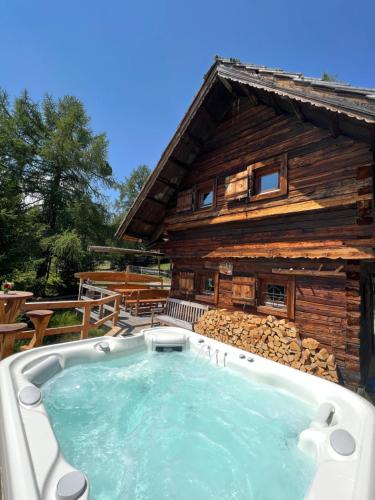 a hot tub in front of a log cabin at Almhütte Kärnten in Maltaberg