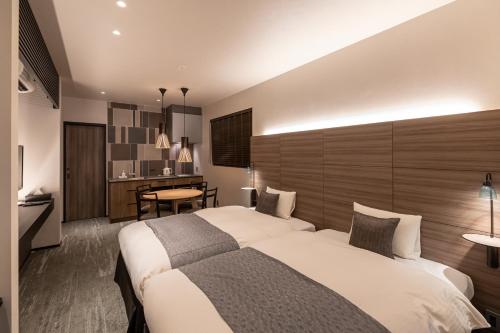 a hotel room with two beds and a table at Hotel Liberte Kyoto Gojo in Kyoto