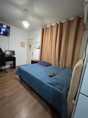 1 dormitorio con cama, escritorio y piano en Kitnet 150m da praia c/ garagem e portaria 24h, en Praia Grande