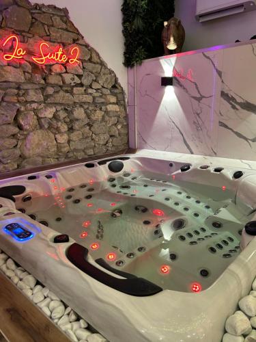 a hot tub in a room with a stone wall at Grenoble LA SUITE 2 spa jaccuzzi et sauna privatif in Grenoble