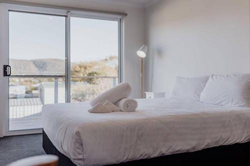 a bedroom with a white bed with a large window at Cedar House ~ Family Fun! in Bicheno