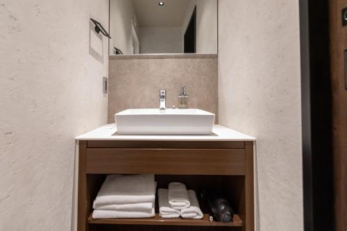 a bathroom with a sink and towels on a shelf at Hotel Liberte Kyoto Gojo in Kyoto