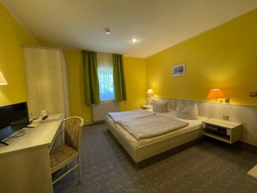 a bedroom with a bed and a desk and a television at Eichenhof Hotel Garni in Groß Köris