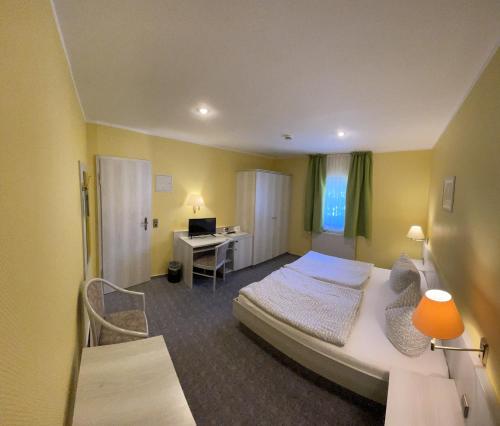 a bedroom with a bed and a desk with a computer at Eichenhof Hotel Garni in Groß Köris