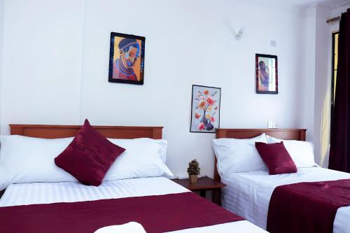 - une chambre avec 2 lits dotés d'oreillers rouges et blancs dans l'établissement Bamburi 2BR Apartment, à Mombasa