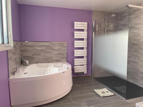 een badkamer met een bad en een paarse muur bij À 900 M de l'entrée du Circuit des 24 heures in Le Mans