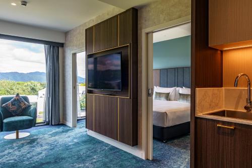 um quarto de hotel com um quarto com uma cama e uma televisão em The Sebel Wellington Lower Hutt em Lower Hutt