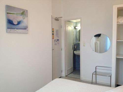 a bedroom with a bed and a mirror at Au Nouvel Hôtel in Toulon