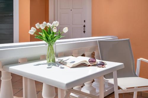 a white table with a vase of flowers and a vase of tulips at Menorca Cristina by Mauter Villas in Cala Blanca