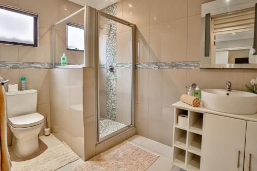 a bathroom with a shower and a toilet and a sink at Salt Rock Beach Home in Sheffield Beach