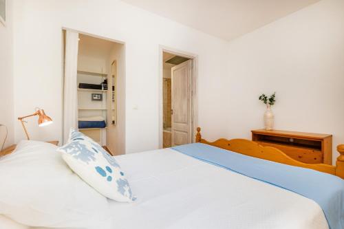 a bedroom with a bed with white sheets and blue pillows at Casa Jaume A in Artá