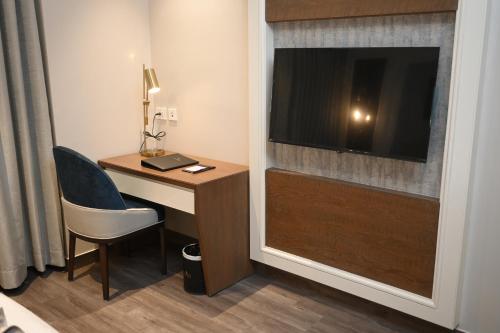 a hotel room with a desk with a television and a chair at Hotel Apricia in Ludhiana