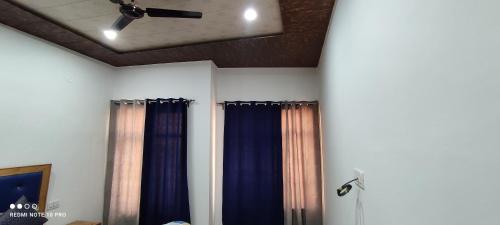 Camera con tende blu e ventilatore a soffitto. di Noor Guest House a Leh