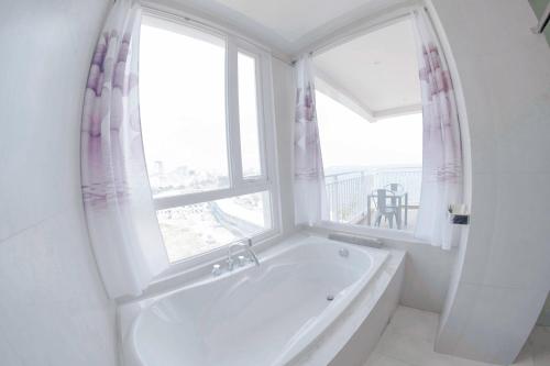 a white bathroom with a tub and a window at La Vogue Boutique Hotel & Casino in Sihanoukville