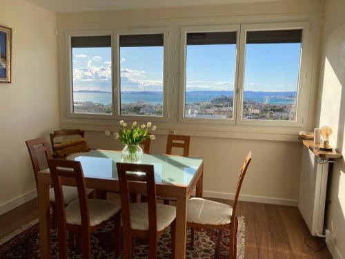une salle à manger avec une table, des chaises et des fenêtres dans l'établissement Mer et Pinède Marseille Calanques, à Marseille