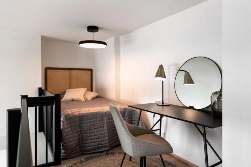 a bedroom with a bed and a desk and a mirror at Loft apartment with lake views in Tampere