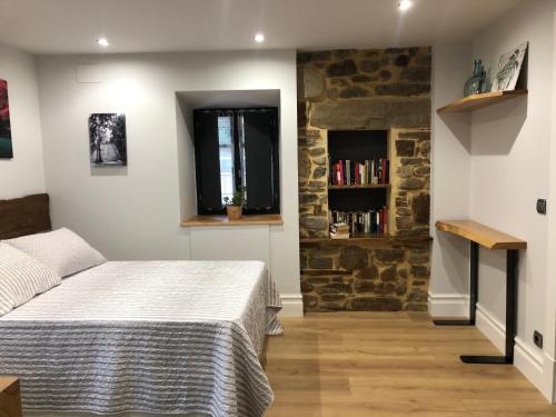 a bedroom with a bed and a stone wall at Golliber Baserrie in Areatza