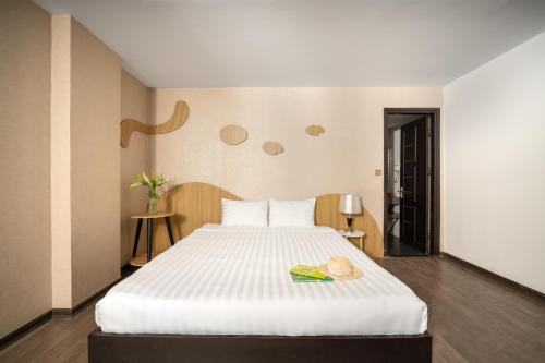 a bedroom with a large white bed with a book at Hanami Hotel Danang in Da Nang