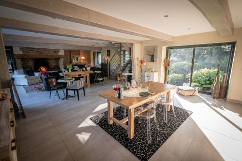 sala de estar con mesa, sillas y chimenea en Le Manoir de la Campagne en Yébleron