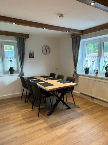 a dining room with a table and chairs and windows at Ferienwohnungen LODGE-B in Weissenbach am Lech