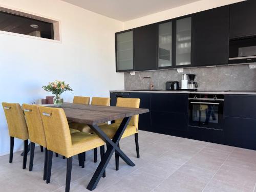 a kitchen with a wooden table and yellow chairs at Villa Resort Apartments by Hiekka Booking in Kalajoki
