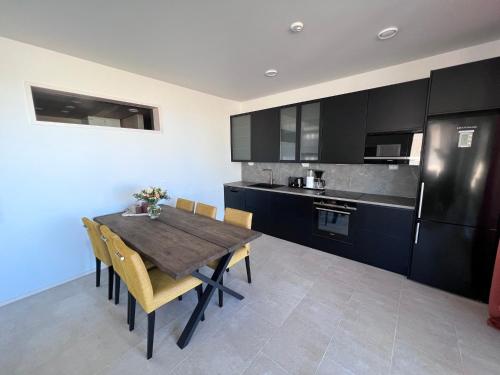 Villa Resort Apartments by Hiekka Booking في كالايوكي: مطبخ مع طاولة وكراسي خشبية وثلاجة