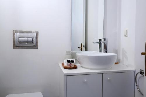 a white bathroom with a sink and a mirror at Sti Chora Apartments in Lefkada Town