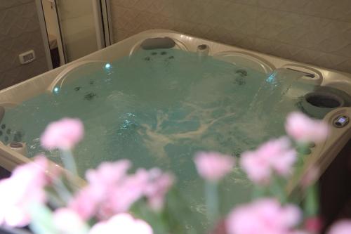 une baignoire remplie d'eau verte avec des fleurs roses dans l'établissement צימר ספא, à Kefar Weradim