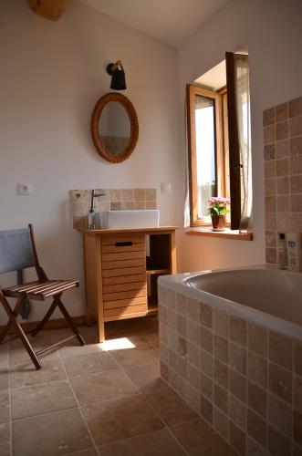 ein Badezimmer mit einer Badewanne, einem Waschbecken und einem Spiegel in der Unterkunft Le Petit Riousset, gîte à la campagne, piscine, petit-dèj in Montvendre
