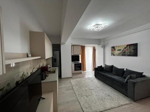 ein Wohnzimmer mit einem schwarzen Sofa und einer Küche in der Unterkunft Relaxing and Beautiful Apartments in Centre of Historical Suceava in Suceava