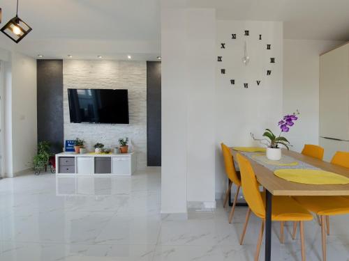a dining room with a table and a clock on a wall at Apartment Harmony in Umag