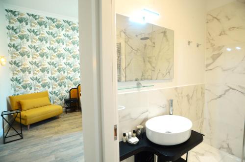 bagno con lavandino bianco e sedia gialla di San Cosimato 40 guesthouse a Roma