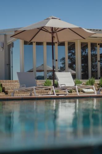 a pool with two lounge chairs and an umbrella at La Dehesa de Don Pedro in Monesterio