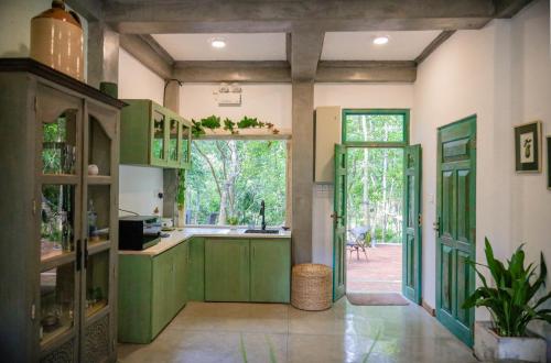 a kitchen with green cabinets and an open door at Tranquilisle in Kandy