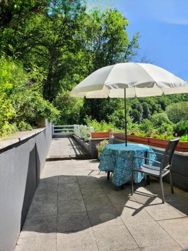 a table with an umbrella on a patio at Gästehaus Beurener Mühle in Bad Bertrich