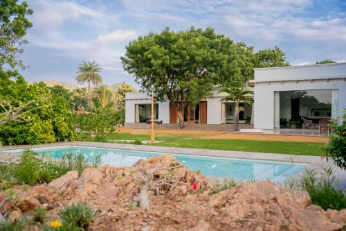 a house with a swimming pool in front of a yard at YAAN Udaipur in Udaipur