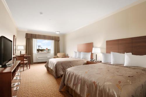 a hotel room with two beds and a flat screen tv at Ramada by Wyndham College Station in College Station