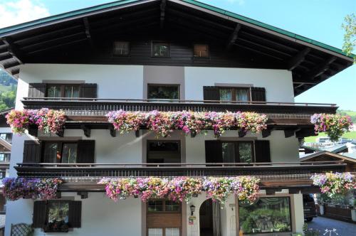 a white building with flowers on the balcony at Pension Hochtor in Saalbach Hinterglemm