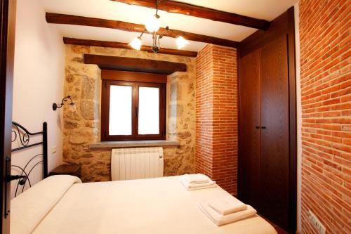 a bedroom with a white bed and a brick wall at Apartamento Puerta del Sol de 1 habitación in Candelario