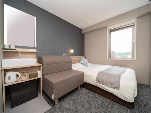 a hotel room with a bed and a chair at Super Hotel Premier Sendai Kokubuncho Tennenonsen in Sendai