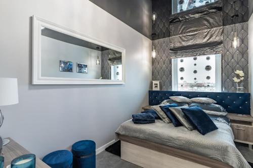 een slaapkamer met een bed met een blauw hoofdeinde en een spiegel bij #MazuryGlamour in Giżycko