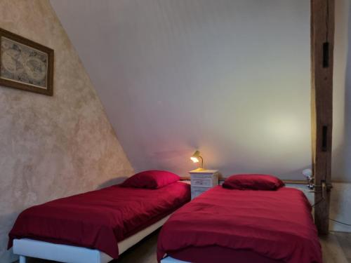 2 bedden in een kamer met een rood dekbed bij Gîte tout confort dans le Perche in Margon